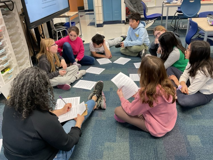 Photo of students working on the floor as they read papers
